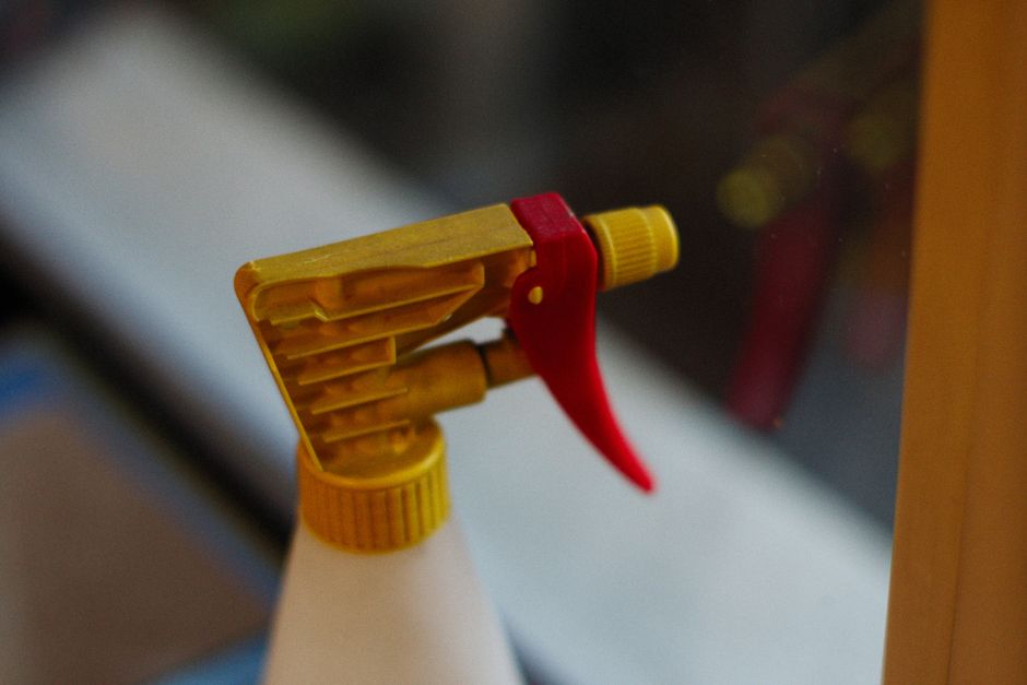 Detailed view of a yellow and red spray bottle nozzle in focus.